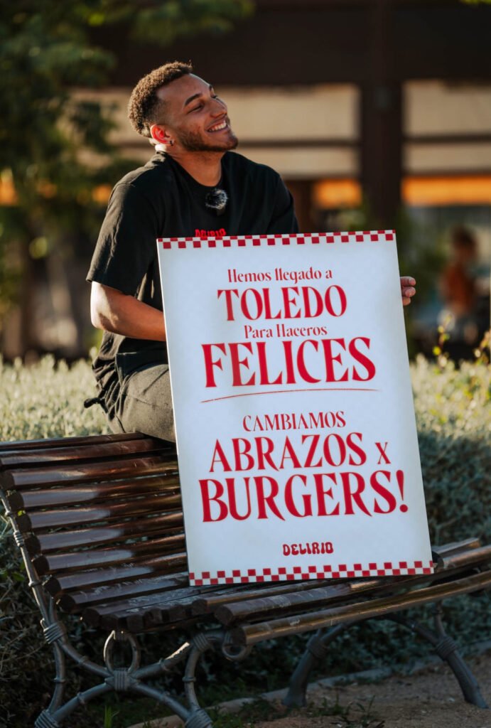 Joven sosteniendo un cartel de Delirio Smash Burger anunciando su llegada a Toledo